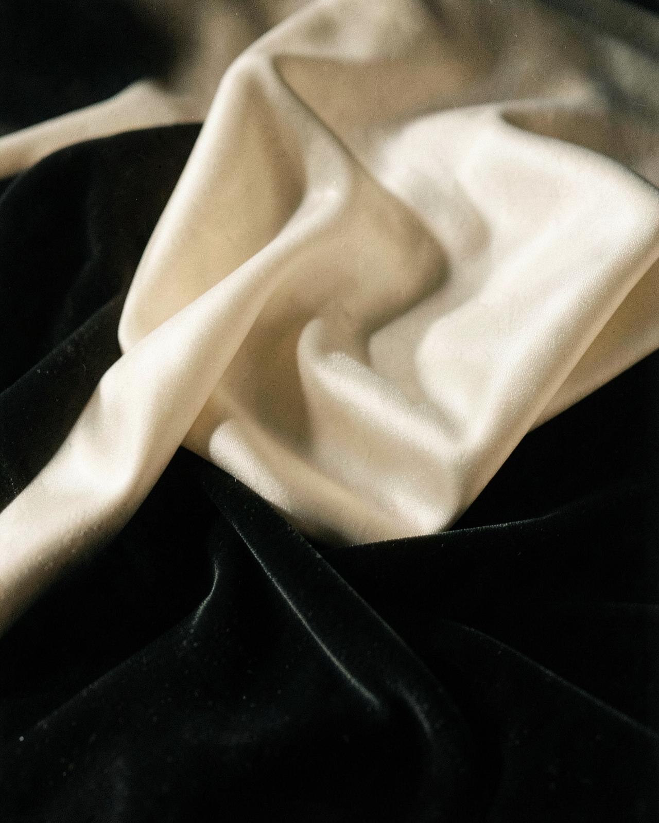 Folds of ivory silk against dark velvet in low directional light